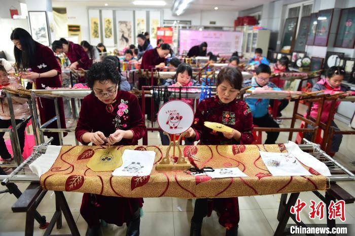江西省級非遺豫章繡傳承人手把手指導(dǎo)小學(xué)生繡制2022年北京冬奧會吉祥物“冰墩墩”形象。　喻云亮 攝