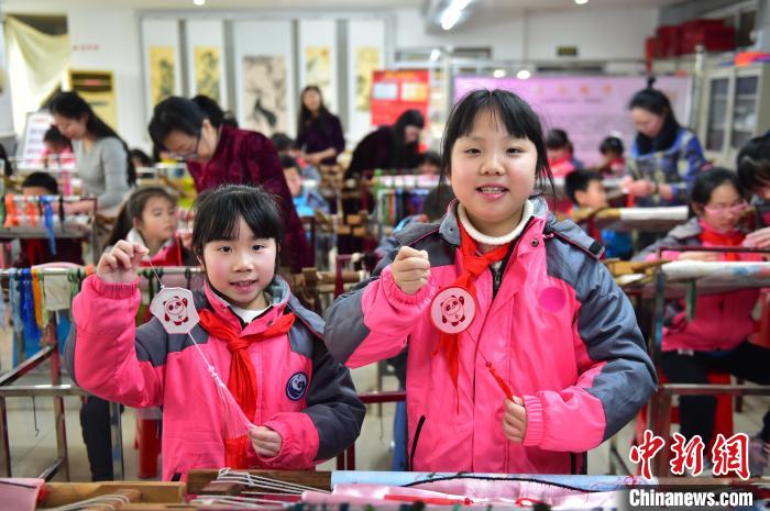 圖為小學(xué)生展示繡制好的2022年北京冬奧會吉祥物“冰墩墩”形象?！∮髟屏?攝