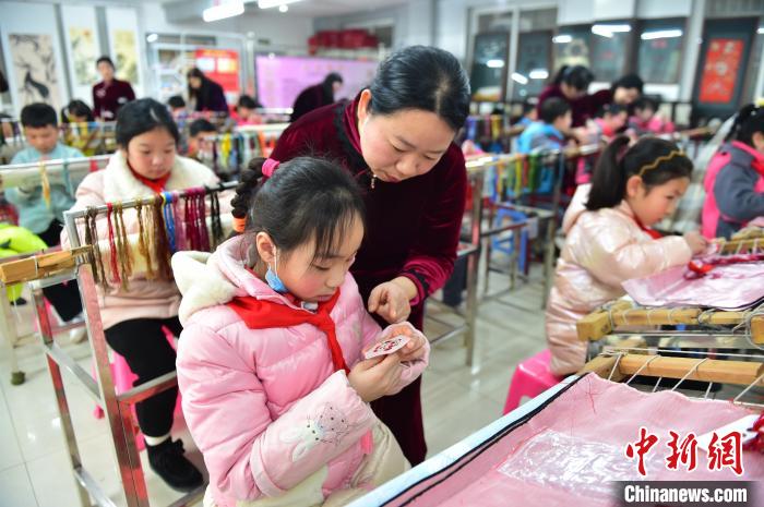 江西省級非遺豫章繡傳承人手把手指導(dǎo)小學(xué)生繡制2022年北京冬奧會吉祥物“冰墩墩”形象。　喻云亮 攝