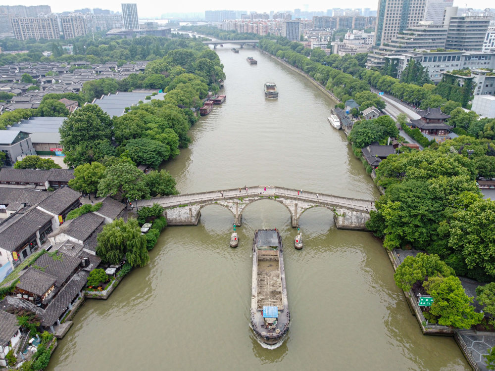 5月27日，一艘貨船駛過京杭大運(yùn)河南端標(biāo)志建筑杭州拱宸橋。(無(wú)人機(jī)照片)新華社記者江漢 攝