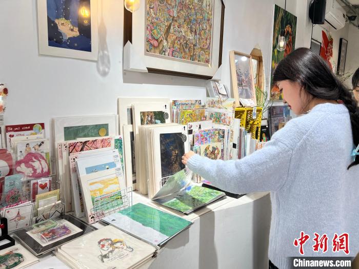 圖為藝術(shù)品商店內(nèi)，顧客挑選插畫作品。　鐘旖 攝