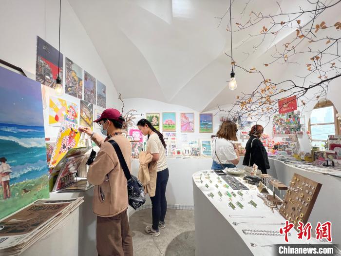 圖為藝術(shù)品商店內(nèi)，顧客挑選插畫作品?！＄婌?攝