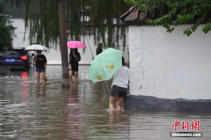7月31日，市民行走在雨中的北京房山區(qū)瓦窯頭村。北京市氣象臺當(dāng)日10時發(fā)布分區(qū)域暴雨紅色預(yù)警信號。北京市水文總站發(fā)布洪水紅色預(yù)警，預(yù)計當(dāng)日12時至14時，房山區(qū)大石河流域?qū)⒊霈F(xiàn)紅色預(yù)警標(biāo)準(zhǔn)洪水。<a target='_blank' href='/'><p  align=