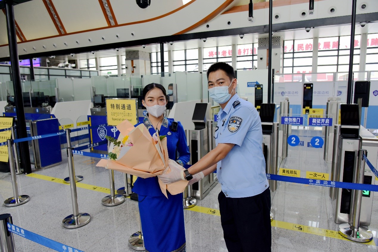 磨憨出入境邊防檢查站民警為中老鐵路第100萬(wàn)名出入境旅客，D888次國(guó)際旅客列車?yán)蠐爰藙?wù)員森達(dá)拉·妮緹婭（Sengdala Nitiya），送上鮮花。黃遠(yuǎn)飛 攝