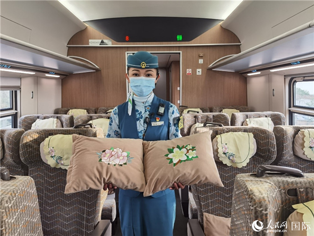 趙瑩靜展示中老鐵路國際旅客列車?yán)飵в兄袊档せê屠蠐胝及突ù汤C圖案的靠墊。人民網(wǎng)記者 杜明明攝