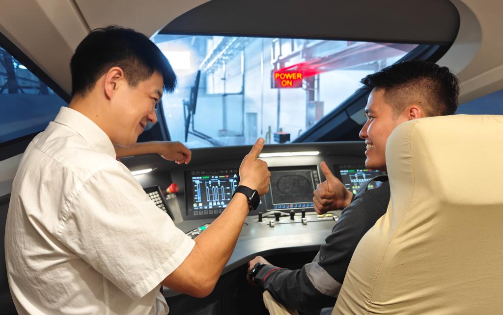 8月25日，在印度尼西亞萬隆的雅萬高鐵德卡魯爾動車所內(nèi)，中國師傅穆振（左）在向印尼火車司機(jī)塞蒂亞萬講解動車組出庫前的上電作業(yè)。