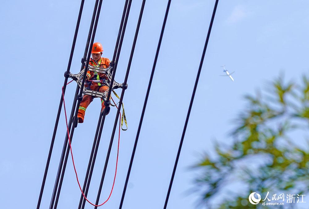 3月11日，在浙江省諸暨市河上鎮(zhèn)，浙江省送變電工程有限公司檢修人員在高空的導(dǎo)線上進(jìn)行線路檢修維護(hù)。人民網(wǎng) 章勇濤攝
