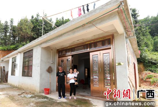 7月4日，在廣西柳州市融安縣大坡鄉(xiāng)崗偉村，脫貧戶肖裕安（左）與妻子、外孫在改造后的房屋前合影。覃慶和 攝