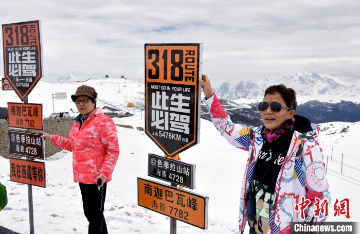 圖為5月14日，西藏林芝色季拉山觀景臺(tái)，游客與南迦巴瓦峰合影。　李林 攝