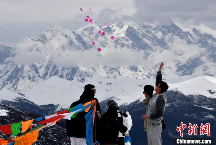 圖為5月14日，游客在西藏林芝色季拉山觀景臺(tái)拋灑“隆達(dá)”(風(fēng)馬旗，藏族民眾的一種祈福方式)。　李林 攝