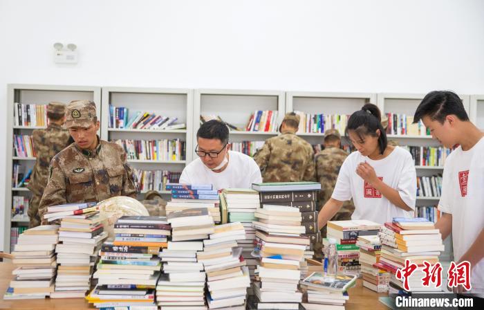 圖為志愿者們和邊防戰(zhàn)士整理圖書?！詵| 攝