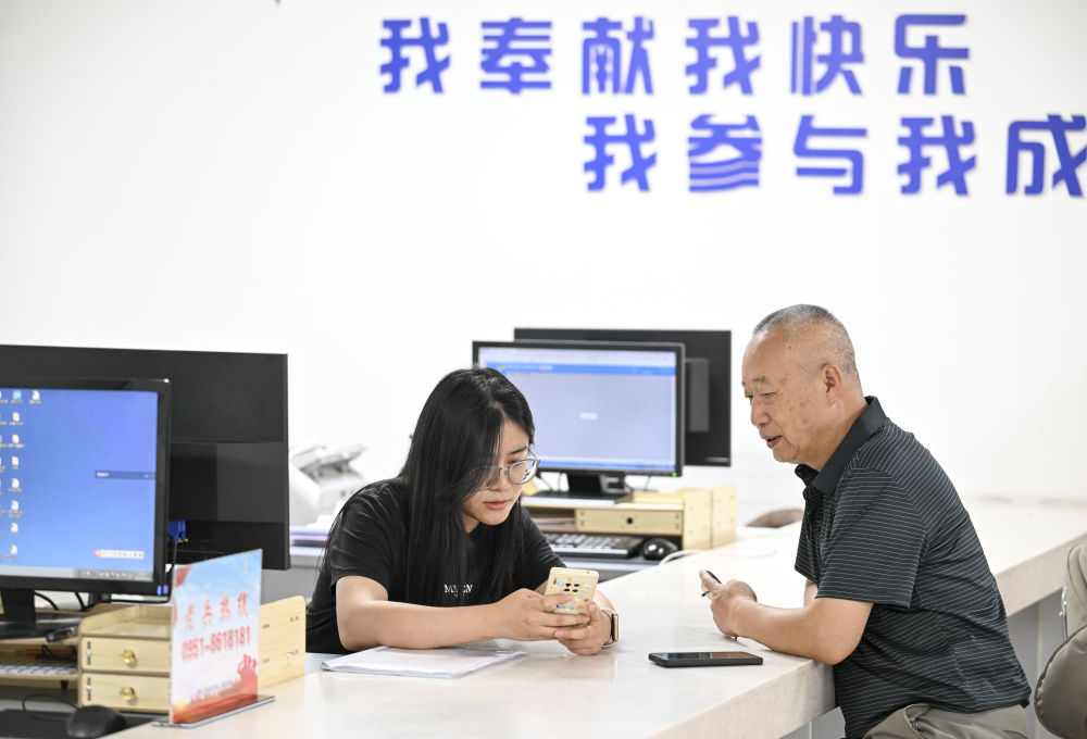 2024年6月20日，在寧夏銀川市金鳳區(qū)長(zhǎng)城花園社區(qū)黨群服務(wù)中心，工作人員幫助居民辦理業(yè)務(wù)。圖片來(lái)源 新華社