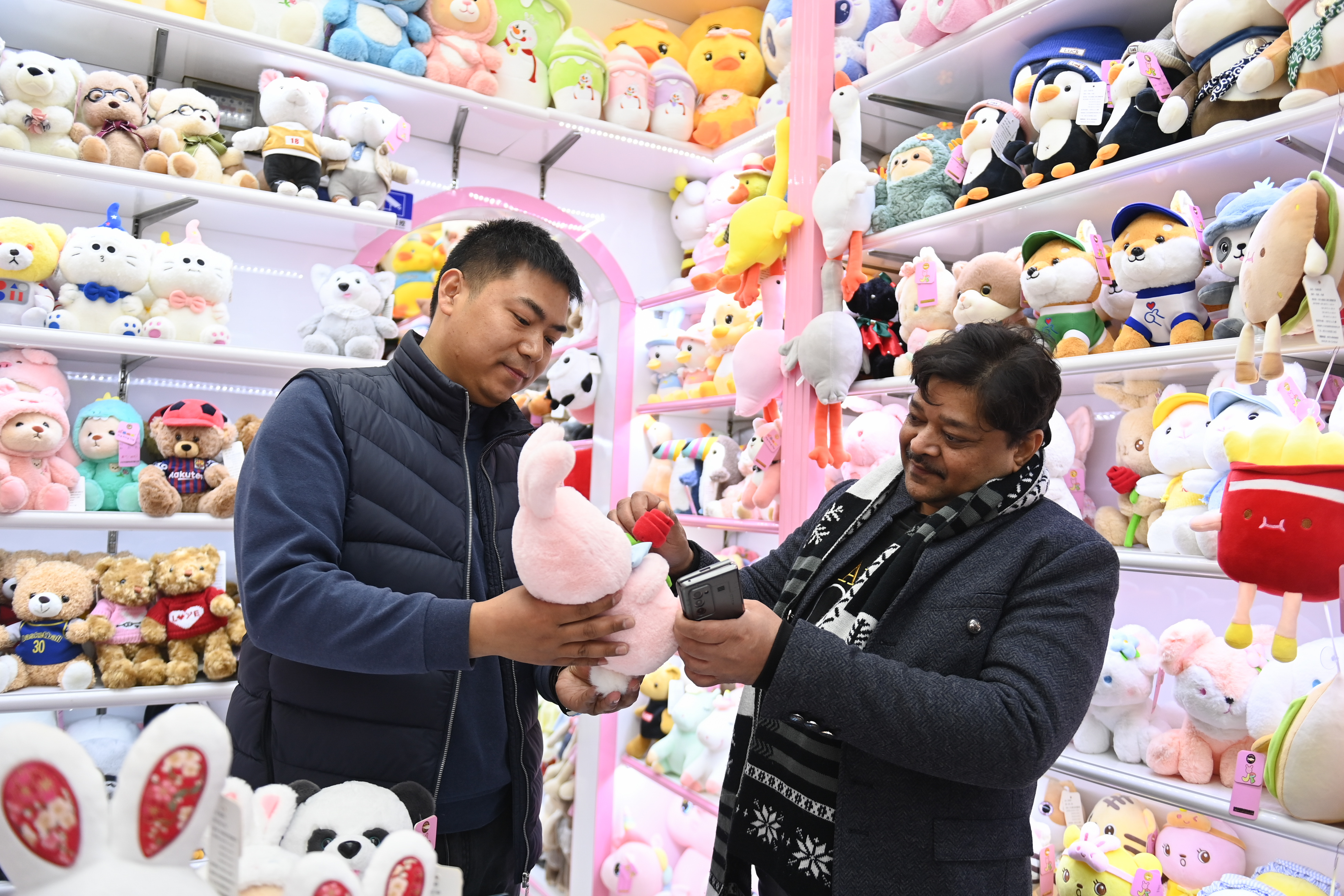 2023年2月2日，來自印度的客商（右）在義烏國際商貿城的一家玩具店鋪內選購。