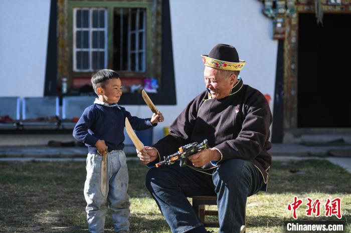 圖為米林縣扎西繞登鄉(xiāng)彩門村64歲的洛桑帶著孫子巴桑在院子的草地上玩耍?！『闻罾?攝