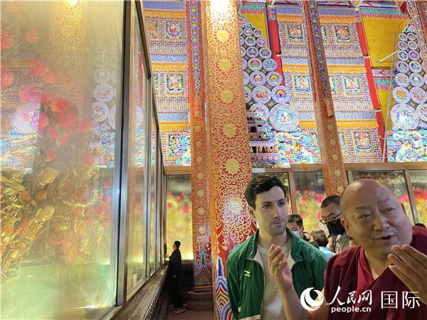 7月25日，省級非物質(zhì)文化遺產(chǎn)項目塔爾寺酥油花的代表性傳承人朋措堅參（右）在塔爾寺酥油花館講解酥油花的制作過程。人民網(wǎng) 謝瑩攝