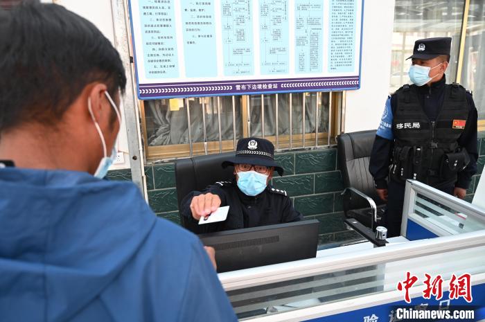 圖為移民管理警察登記完身份信息后將證件歸還給行人?！≮w朗 攝