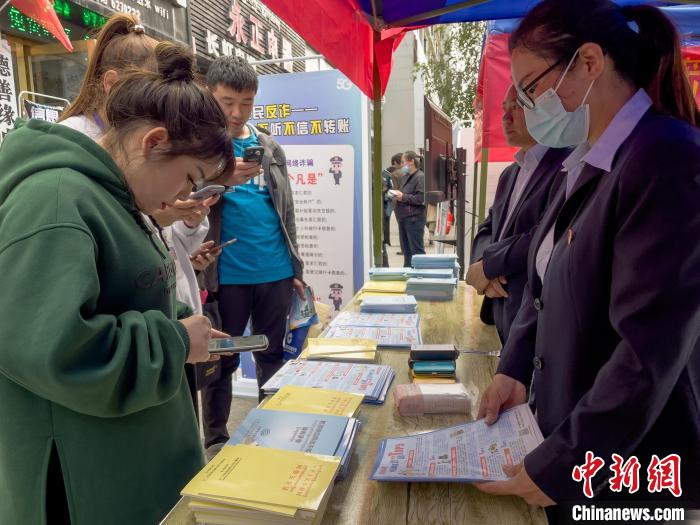 圖為工作人員正在向路過市民介紹國家反詐中心軟件的功能?！≈x牧 攝