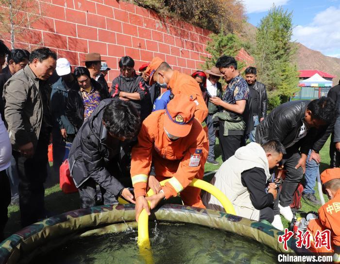 圖為森林消防員為護(hù)林員講解滅火裝備的使用方法?！〔际猩窒乐ш?供圖