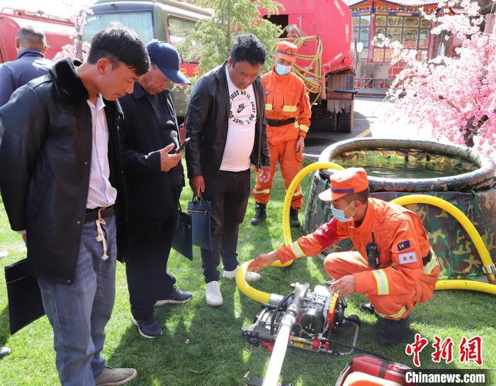 圖為森林消防員為護(hù)林員講解滅火裝備的使用方法?！〔际猩窒乐ш?供圖