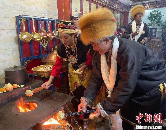 圖為人們在火上烤節(jié)日美食“結(jié)達”?！∪轿木?攝