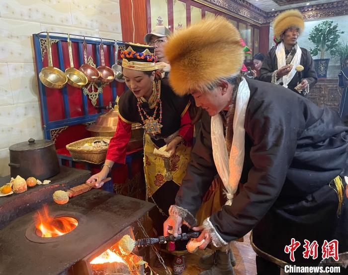 圖為人們在火上烤節(jié)日美食“結(jié)達”?！∪轿木?攝