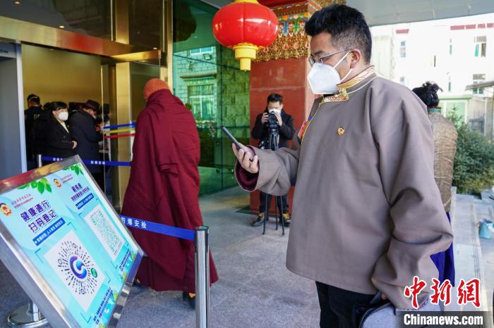 圖為政協(xié)委員掃場所碼進(jìn)入會場?！〗w波 攝