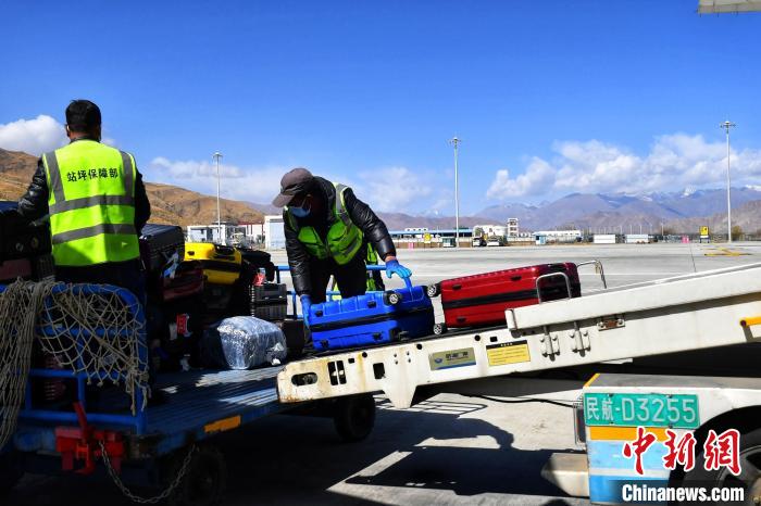 圖為機場工作人員傳送旅客行李箱?！≈芎?攝